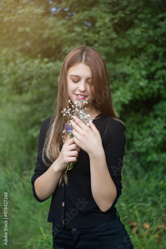 Young woman with a small bouquet of wildflowers. Vertical photo.