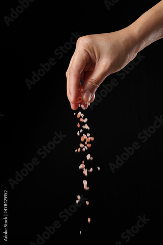 Hand holding pink salt on black background