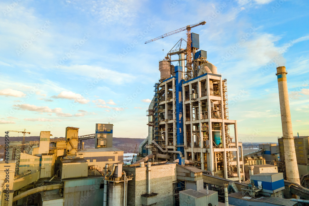 Aerial view of cement plant with high factory structure and tower crane at industrial production area at sunset Aerial view of cement plant with high factory structure and tower crane at industrial production area at sunset