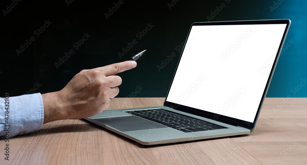 Businessman hand holding pen to display laptop and calculator on table Businessman hand holding pen to display laptop and calculator on table