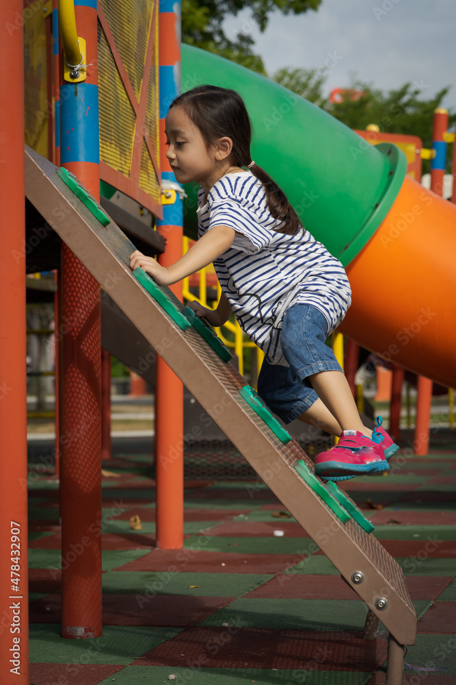 Fototapeta premium Little girl playing at the playground. Climbing and active.