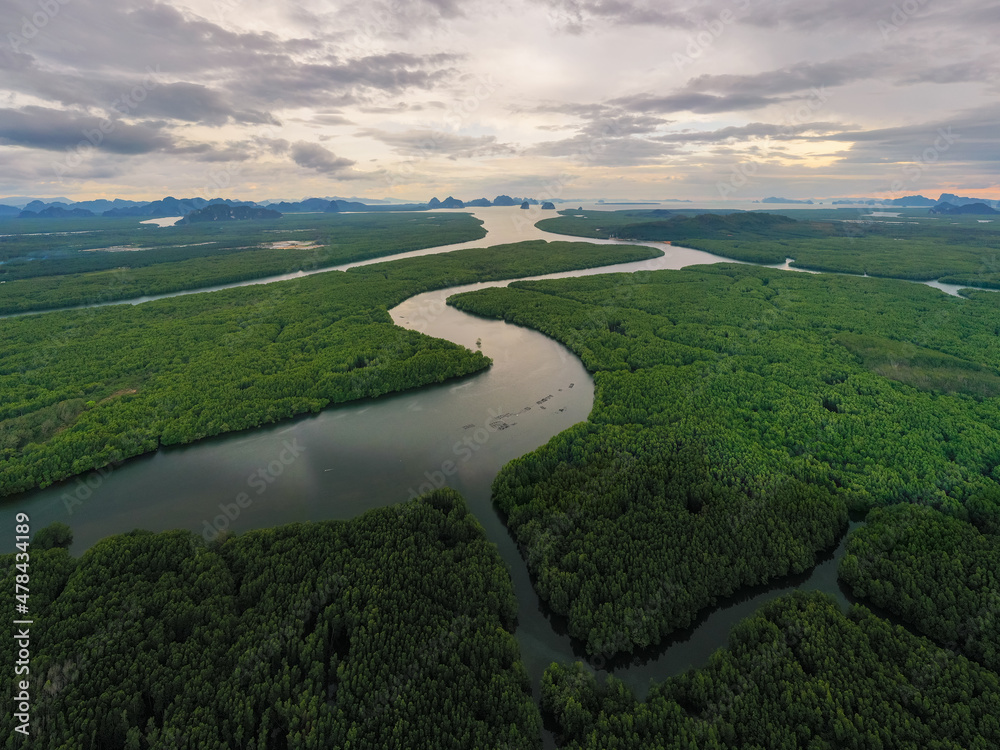 Fototapeta premium Aerial Drone footage flying over mangroves and lush rainforest in Phangnga bay Thailand The view is of mountainous islands and dramatic orange sunrise over the ocean