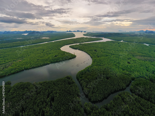 Aerial Drone footage flying over mangroves and lush rainforest in Phangnga bay Thailand The view is of mountainous islands and dramatic orange sunrise over the ocean