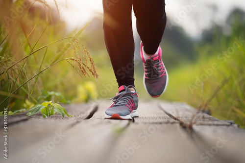 woman feet running on wooden path in field