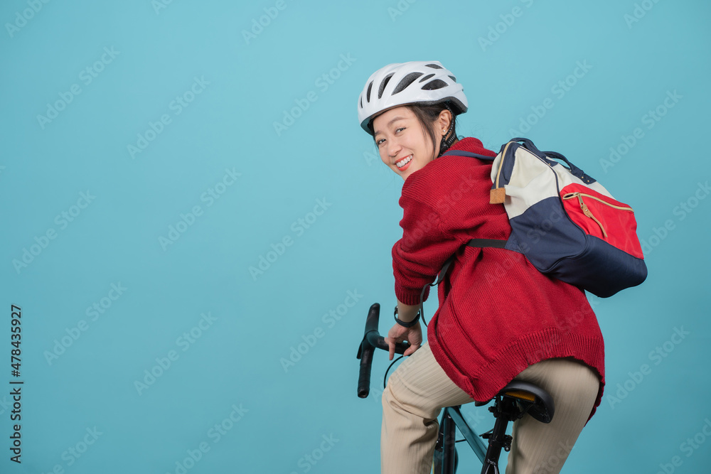 Beautiful asian woman is cycling and looked at the camera on a blue background. She turned her back to the camera. Beautiful asian woman is cycling and looked at the camera on a blue background. She turned her back to the camera.