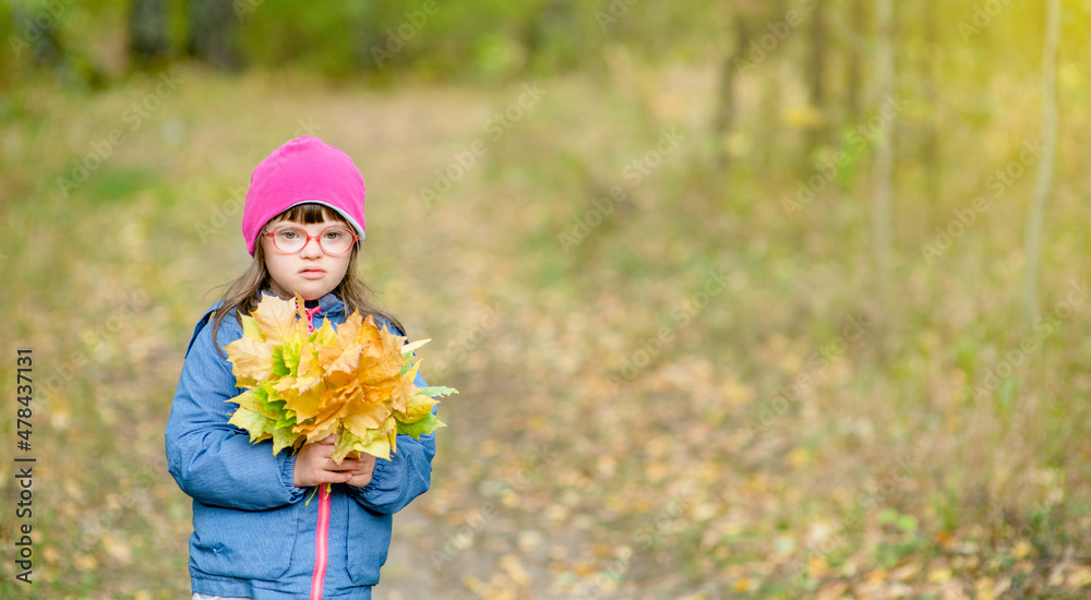 Happy young girl with Downs syndrom holds bouquet of autumn leaves. Empty space for text Happy young girl with Downs syndrom holds bouquet of autumn leaves. Empty space for text