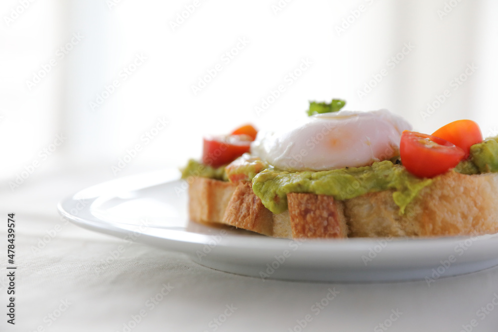 Poached eggs with avocado on toast in white background