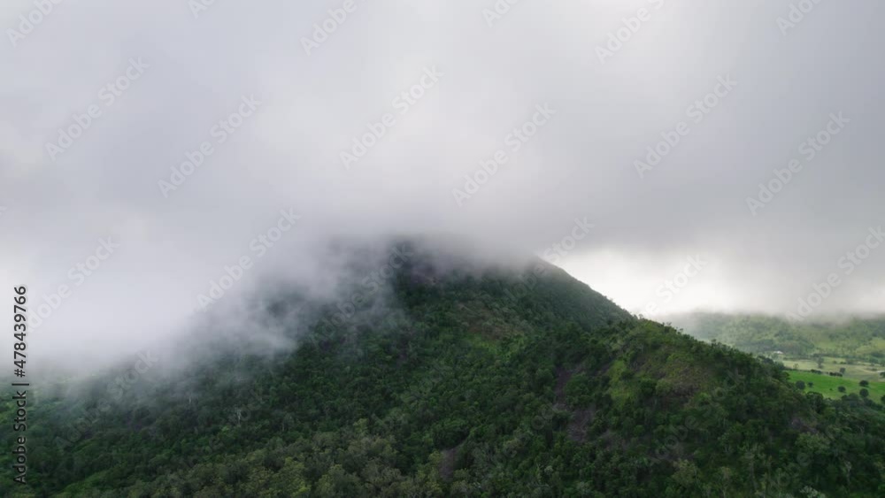 Drone shot of clouds and fog hanging over moody green Australian mountain with gumtrees Drone shot of clouds and fog hanging over moody green Australian mountain with gumtrees