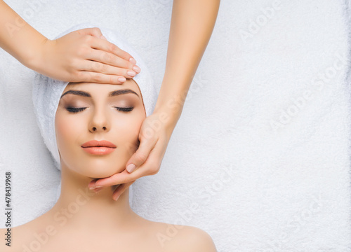 Young and healthy woman gets massage treatments for face, skin and neck in the spa salon. Health, wellness and rejuvenation concept.
