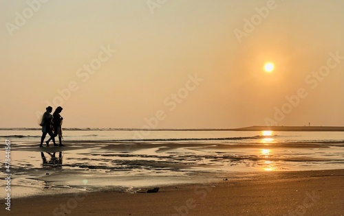 couple walking on the beach at sunset © Aman