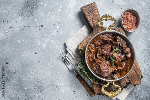 German braised beef cheeks in brown red wine sauce. Gray background. Top view. Copy space photo