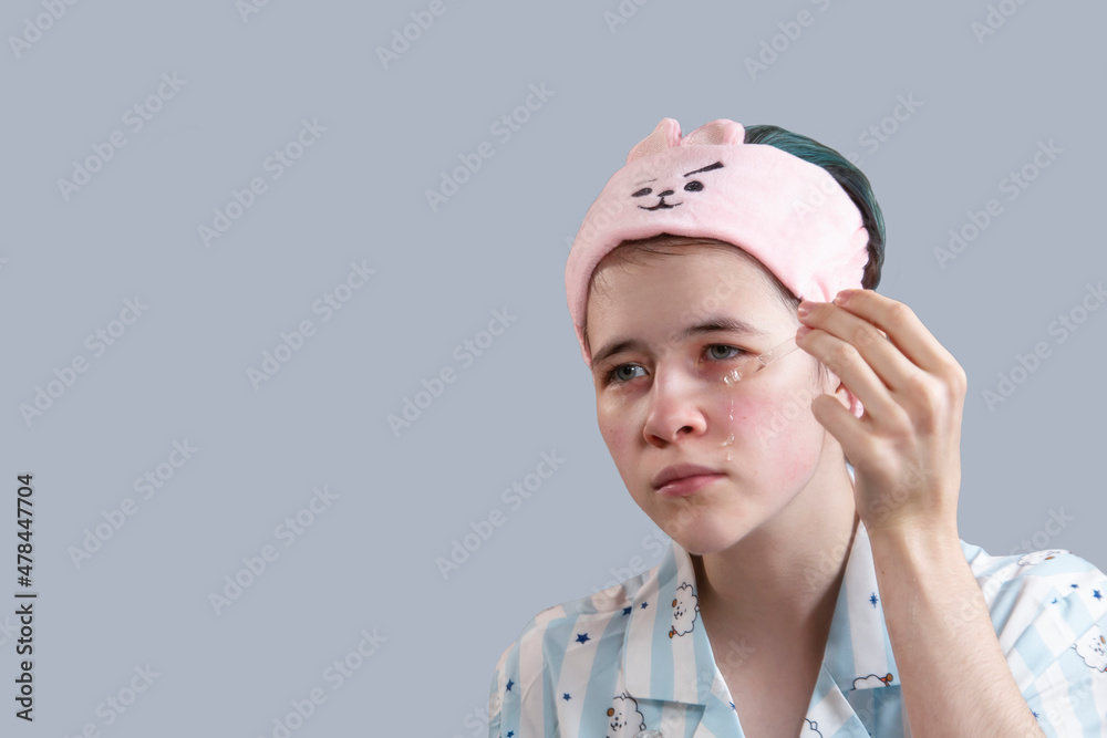 A young girl applies a cosmetic serum to her face. Skin care, healthy lifestyle. Isolate with copy space. A young girl applies a cosmetic serum to her face. Skin care, healthy lifestyle. Isolate with copy space.