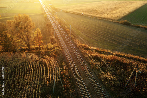 Fotografering Aerial view of railway through agricultural fields at sunset, countryside landsc