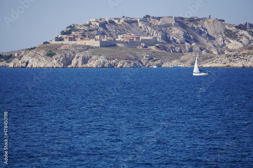view of island des eyglaudes with houses and old stone fort across marseille france with a lone sailboat
