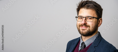 Portrait of one adult caucasian man 30 years old with beard and eyeglasses looking to the camera in front of white wall background wearing suit young businessman success concept copy space