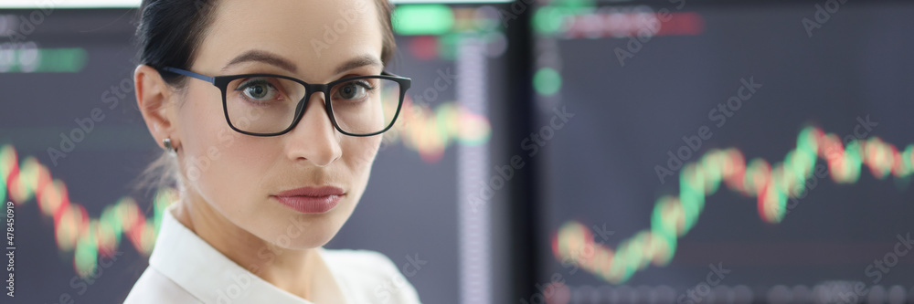 Portrait of businesswoman with glasses on background of electronic stock market analytics closeup Portrait of businesswoman with glasses on background of electronic stock market analytics closeup
