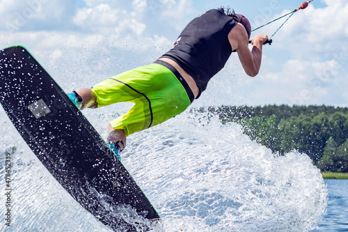 young active professional athlete jumping in the air on a wakeboard, water sports in the river 
