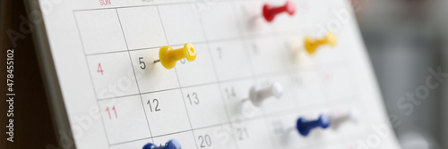 Various color thumb tack pins on calendar as reminder
