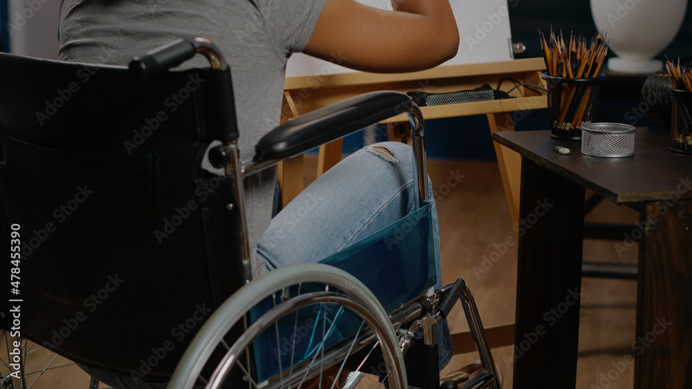 Fototapeta premium Close up of african american woman in wheelchair drawing vase for fine art concept at studio. Black person with disability working on authentic masterpiece with professional tools