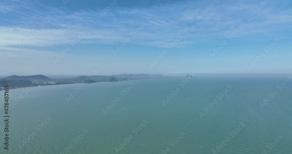 flying above the clean ocean and curve of town with mountain flying above the clean ocean and curve of town with mountain