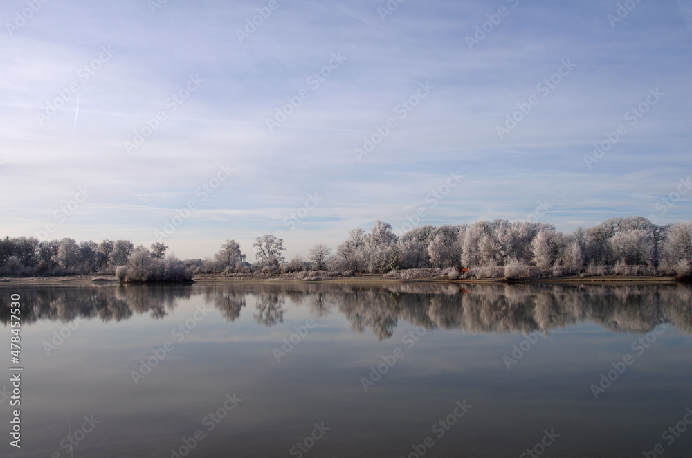 Winterliche Landschaft. Mit Frost überzogene Bäume spiegeln sich im See