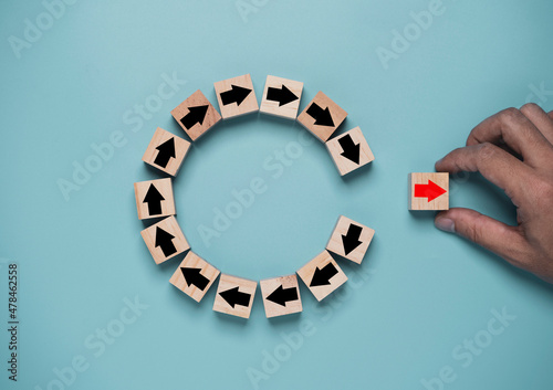 Disruption and technology transformation concept , Hand move out red arrow on wooden block cube move out from circle black arrow on blue background. photo