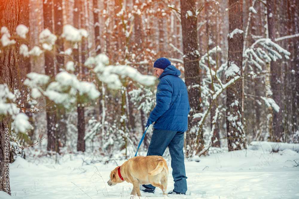 Happy man with dog walking in a winter snowy forest Happy man with dog walking in a winter snowy forest