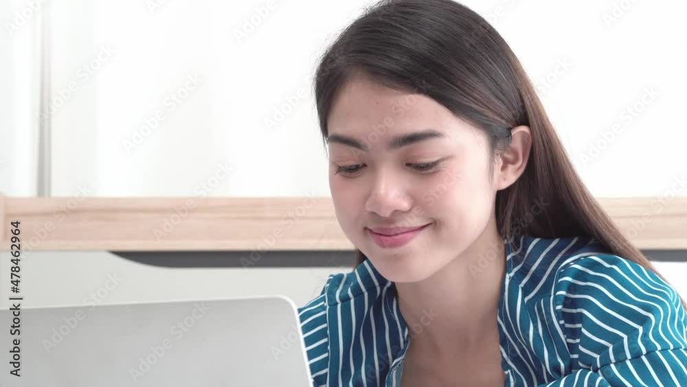 Close up of young beautiful happy Asian woman sit on bed typing on laptop, chat with friends and family, look at computer screen and smile with love and joy. Modern digital lifestyle and communication Close up of young beautiful happy Asian woman sit on bed typing on laptop, chat with friends and family, look at computer screen and smile with love and joy. Modern digital lifestyle and communication