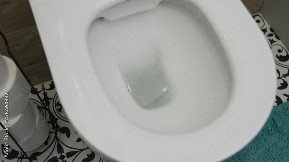 Toilet paper fall in toilet bowl and water flushing. Hygiene concept