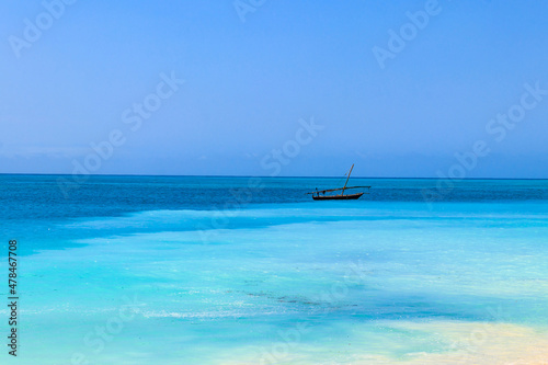 View of tropical sandy Nungwi beach and traditional wooden dhow boat in the Indian ocean on Zanzibar, Tanzania