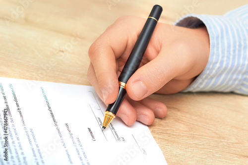Business man's hand holding white paper. Financial planning specialist signing annual report in company's office. Businessman sitting at the desk with accounting papers and ballpoint.