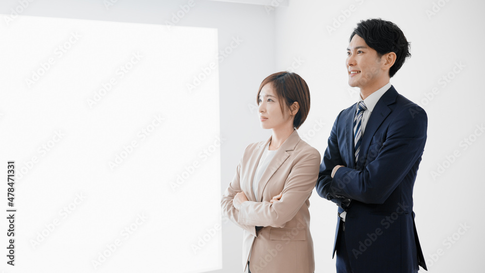 腕組みをして立つビジネスマンとビジネスウーマン