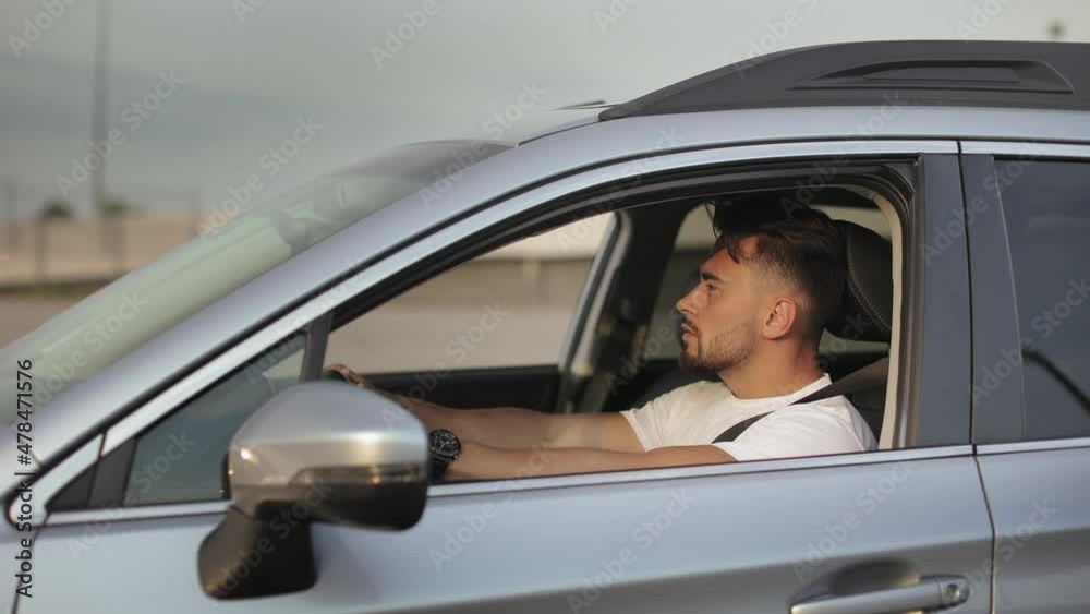 A man is sitting in the car in the driver's seat and putting on his seat belt. He is putting his hands on the steering wheel. 4K 50fps A man is sitting in the car in the driver's seat and putting on his seat belt. He is putting his hands on the steering wheel. 4K 50fps