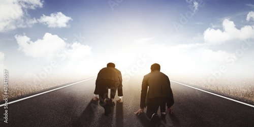 Rear view of two businessmen kneeling on road photo