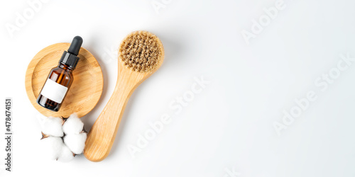 skin exfolation and rejuvination concept. Drop bottle with fruit peeling and face massaging brush with natural bristle on white background with copy space. Banner