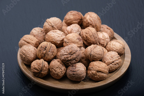 Walnut on black copy space. Group of walnuts on a black background. Nuts on a wooden plate close-up.