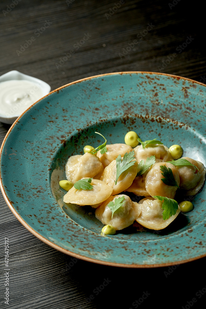 Chinese dumplings stuffed with meat with white sauce in a blue plate on a wooden background