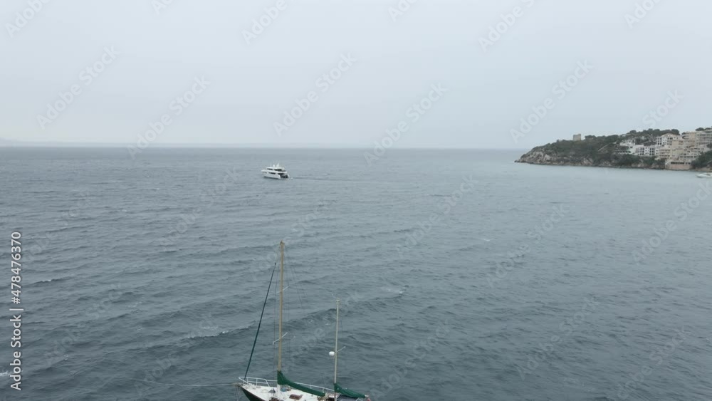 Sailboat And Catamaran Floating In The Ocean On A Chilly, Overcast Day In Mallorca, Spain. - aerial Sailboat And Catamaran Floating In The Ocean On A Chilly, Overcast Day In Mallorca, Spain. - aerial