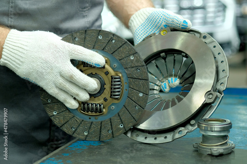 Car spare parts. The clutch kit is in the hands of an auto mechanic. Monitoring of the technical condition of the drive disc, the driven disc and the exhaust bearing. Repair and maintenance in a car s photo