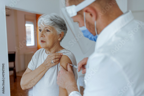 Cropped shot of a young doctor giving a senior woman a vaccination. Virus protection. Doctor giving injection to patient at home, close up. Vaccination day. Healthcare and medicine concept.