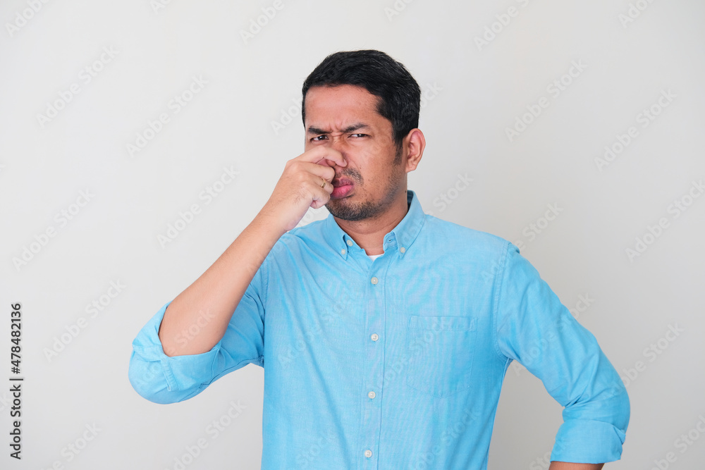 Adult Asian man closed his nose with hand when smell something bad Adult Asian man closed his nose with hand when smell something bad