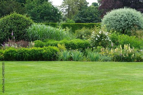 Scenic View of a Beautiful English Style Landscape Garden with a Green Mowed Lawn and Colourful Flower Bed