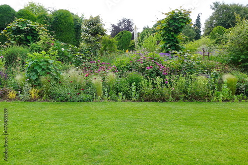 Scenic View of a Beautiful English Style Landscape Garden with a Green Mowed Lawn, Colourful Flower Bed and Leafy Trees