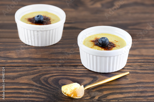 Homemade vegan creme brulee with blueberries in bowls on a wooden table.