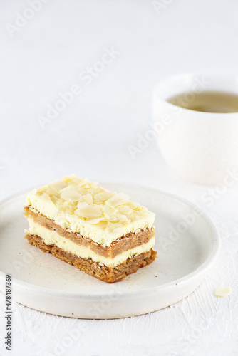 A piece of lemon cake with almonds in a plate with a cup of tea. Sugar  gluten and lactose free and vegan.