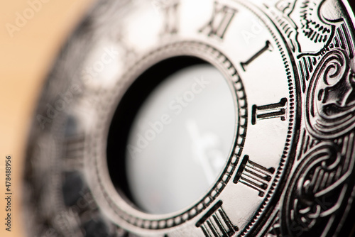 Pocket watch, beautiful details of a pocket watch positioned on a rustic wooden surface, selective focus.
