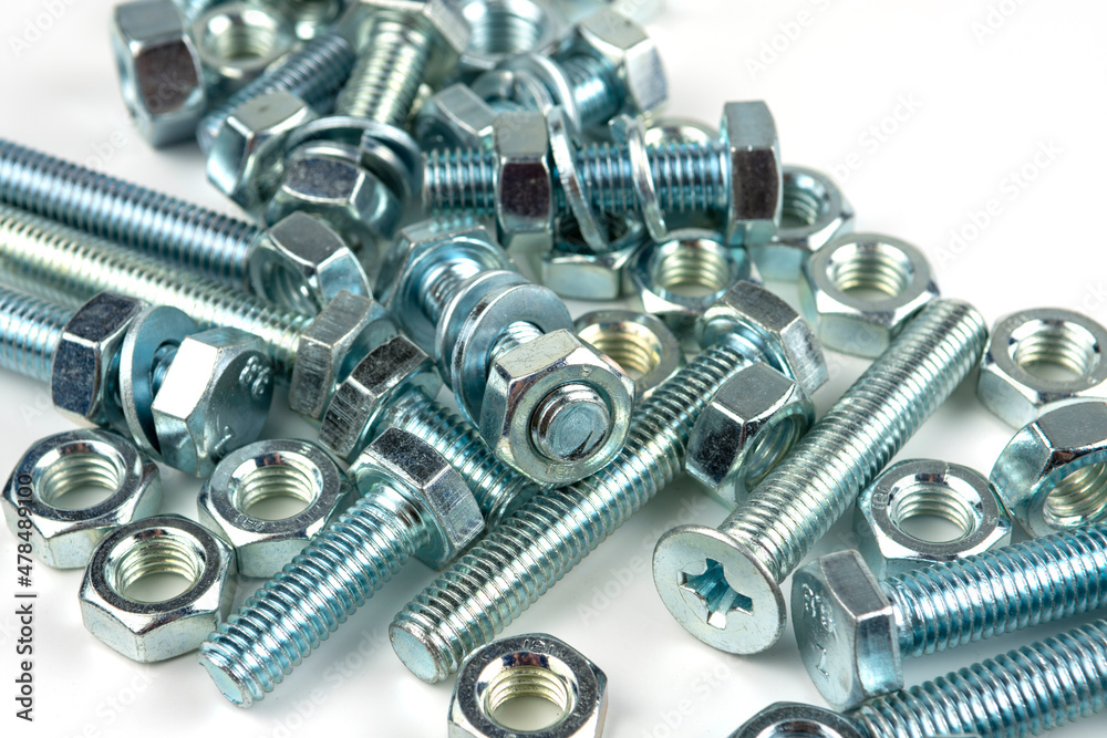 A large group of silver fasteners for fastening structures. Bolts and nuts with washers close-up on a white background. A large group of silver fasteners for fastening structures. Bolts and nuts with washers close-up on a white background.