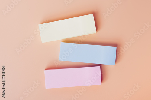 Blank stickers in various pastel colors, yellow, blue, pink on the office desk for entering a text. Top view and space for text. Close up