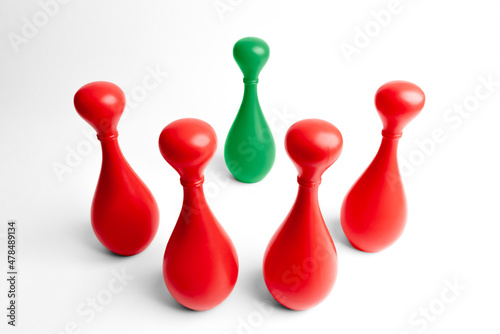 Photo Four red skittles standing around a green one in a threatening way