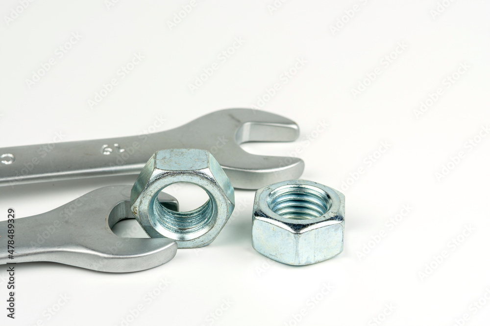 A small group of silver fasteners to secure the structure. Nuts close-up on a white background. Several wrenches. A small group of silver fasteners to secure the structure. Nuts close-up on a white background. Several wrenches.